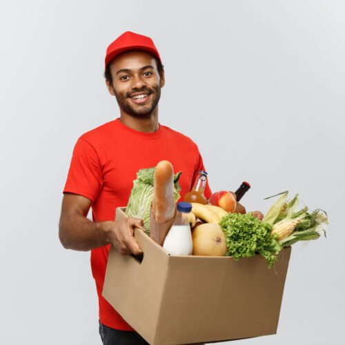 Delivery Concept - Handsome African American delivery man carrying package box of grocery food and drink from store. Isolated on Grey studio Background. Copy Space.